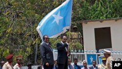 Le président somalien Mohamed Abdullahi Farmajo, à centre-droite, tient un drapeau somalien lors de la cérémonie avec l'ancien président Hassan Sheikh Mohamud, à Mogadiscio, Somalie, le 16 février 2017. 