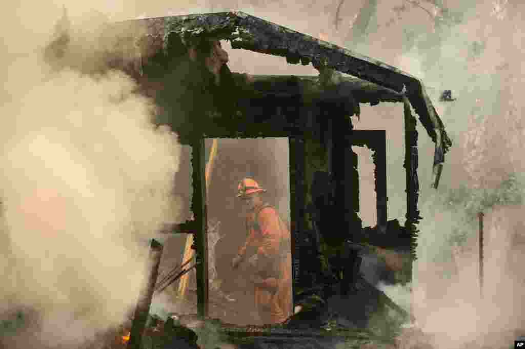 An inmate firefighter examines a burning structure while battling the Loma fire near Morgan Hill, California, Sept. 28, 2016.