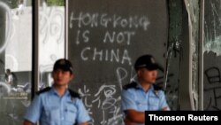 Policemen stand in front of graffiti on the walls of the Legislative Council, a day after protesters broke into the building in Hong Kong, July 2, 2019. 