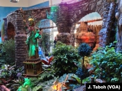 A model of the Statue of Liberty, made out of plant parts, towers over a lush landscape of dozens of National Park sites.