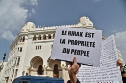 FILE - Algerians carry placards during an anti-government demonstration in the capital Algiers, April 2, 2021. The placard reads in French: "The Hirak belongs to the people."