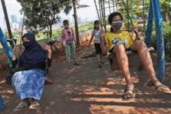 Anak-anak yang memakai masker, beraktivitas di luar ruangan dengan bermain ayunan di tengah pandemi di Jakarta.