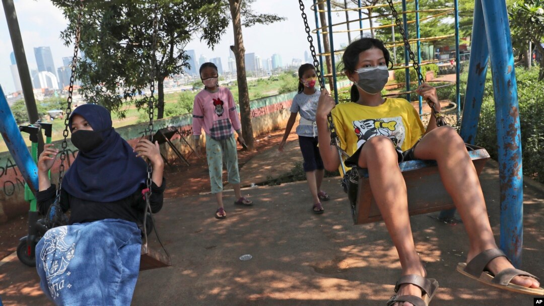Anak-anak perempuan dengan memakai masker, bermain ayunan di tengah pandemi di Jakarta (foto: ilustrasi). 