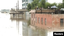 North Koreans are seen on the tops of houses at a flooded village in Anju, July 30, 2012.