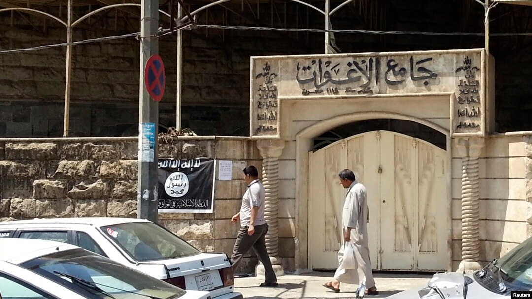 Warga melewati spanduk bertuliskan lambang Negara Islam (ISIS) di Mosul, Irak. (Foto: Dok)