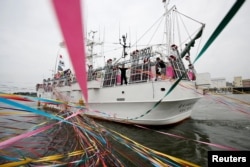 A crew member of a squid fishing ship Wakashio-maru No. 85 waves to the relatives as they depart the fishing port in Sakata, Yamagata prefecture, Japan, June 6, 2018.