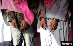 FILE - Two men in handcuffs, whom the police said belong to the Tehreek-e-Taliban Pakistan [TTP] group, are shown during a news conference at the Crime Investigation Department after their arrest, in Karachi, January 2013.