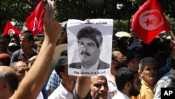Supporters of the Islamist Ennahda movement demonstrate as they chants slogans and hold a picture of assassinated politician Mohamed Brahmi during a demonstration in Tunis, Tunisia, July 26, 2013.