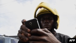 Le pilote du pilote MaxOkada arbore bavoirs et casque aux couleurs de la société lorsqu'il vérifie les informations relatives aux applications, le 4 septembre 2019 à Lagos.