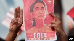 Državljani Mjanmara na Tajlandu drže sliku Aung San Su Ći i tri prsta tokom protesta ispred ambasade Mjanmara u Bangkoku, 8. februara 2021. (Foto: AP)