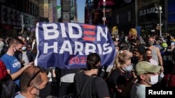 Orang-orang bereaksi ketika media mengumumkan bahwa calon presiden dari Partai Demokrat AS Joe Biden telah memenangkan pemilihan presiden AS 2020, di Times Square di New York City, AS, 7 November 2020. (Foto: REUTERS/Carlo Allegri)