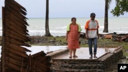 La sobreviviente del tsunami, Kusmiati, camina con su esposo Aden en una villa destruida por el tsunami en Carita, Indonesia, el miércoles 26 de diciembre de 2018. 