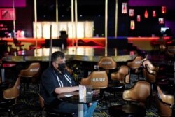 FILE - Jeff Cantrell waits at Larry Flint's Hustler Club strip club after getting his second dose of coronavirus vaccine, May 21, 2021, in Las Vegas. Las Vegas officials held a pop-up vaccine clinic at the strip club.
