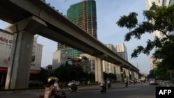 FILE - Motorcyclists ride past the Chinese-funded elevated train line in Hanoi, Vietnam, September 12, 2014.