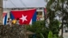 Neighbors look at Cuban flags draped over the windows of opposition activist Yunior Garcia Aguilera's home, in an attempt to stop him from communicating with the outside in Havana, Cuba, Nov. 14, 2021.