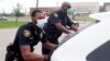 En esta imagen, tomada el 9 de abril de 2020, los agentes de la policía de Dallas Mylon Taylor (izquierda) y Gary Pierre, con mascarillas contra la propagación del coronavirus, empujan un auto que se quedó sin combustible mientras esperaba al reparto semanal de comida para estudi