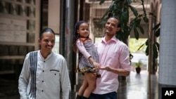 Steven Lacchin, 39, left, and Gerald Erebon, 30, right, holding Steven's daughter, arrive to find out the results of DNA tests they took, which indicated they are half-brothers, Nov. 14, 2019.