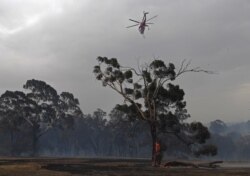 Sikorsky S-64 Skycrane helicopter flies over a burning tree after a fire impacted Clovemont Way, Bundoora in Melbourne, Dec. 30, 2019. (AAP Image/Julian Smith via Reuters)