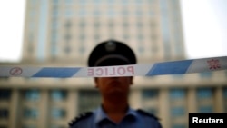 FILE - A police officer stands guard at the entrance to the Jinan Intermediate People's Court on the third day of the trial of ousted Chinese politician Bo Xilai in Jinan, Shandong province, Aug. 24, 2013. 