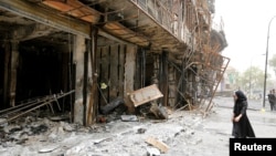 A girl walks past the site after a suicide car bomb attack at the shopping area of Karrada, a largely Shi'ite district, in Baghdad, Iraq, July 4, 2016. 