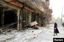 A girl walks past the site after a suicide car bomb attack at the shopping area of Karrada, a largely Shi'ite district, in Baghdad, Iraq, July 4, 2016.