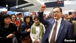 Cambodia's self-exiled opposition party founder Sam Rainsy, who has vowed to return to his home country, gestures to supporters after being prevented from checking-in for a flight from Paris to Bangkok at Roissy Airport in Paris, France Nov. 7, 2019.
