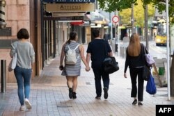 People walk down a street on the first day of the easing of restrictions in Wellington on April 28, 2020, following the COVID-19 coronavirus outbreak.
