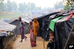 A Rohingya woman holds her child and stands at a makeshift camp near Kutupalong refugee camp in Cox's Bazar, Bangladesh, Oct. 3, 2017. More than half a million Rohingya have fled from Myanmar to Bangladesh in just over a month.