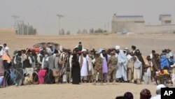 FILE - People en route to Afghanistan wait at the Pakistani border post, Chaman, Wednesday, Aug. 31, 2016.