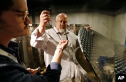 In this April 12, 2018, photo, distillery technician Cole Miller, left, and master distiller in residence George Racz check the temperature of a batch of moonshine cooking in the Mob Museum in Las Vegas.