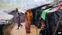 A Rohingya woman holds her child and stands at a makeshift camp near Kutupalong refugee camp in Cox's Bazar, Bangladesh, Oct. 3, 2017. More than half a million Rohingya have fled from Myanmar to Bangladesh in just over a month, the largest refugee crisis to hit Asia in decades.