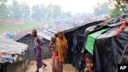 A Rohingya woman holds her child and stands at a makeshift camp near Kutupalong refugee camp in Cox's Bazar, Bangladesh, Oct. 3, 2017. More than half a million Rohingya have fled from Myanmar to Bangladesh in just over a month, the largest refugee crisis 