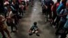 A child sits on the floor as Honduran migrants, part of a caravan trying to reach the U.S., queue to get a mat to rest at a migrant shelter in Guatemala City, Guatemala, Oct. 17, 2018.