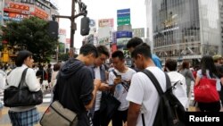 High school students play the augmented reality mobile game "Pokemon Go" by Nintendo on their mobile phone in front of a busy crossing in Shibuya district in Tokyo, Japan, July 22, 2016. 