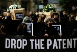 FILE - Global Justice campaigners carry fake coffins to highlight the number of COVID-19 deaths globally, in London, Oct. 12, 2021. Britain is taking part in a World Trade Organization intellectual property meeting to boost the number of vaccinations worldwide.