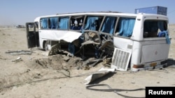 The wreckage of a bus that was damaged in a roadside bomb blast sits beside a road in Ghazni, Afghanistan, July 1, 2012. 