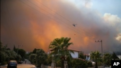 A helicopter flies as a fire engulfs the area in Oren, near Bodrum, Turkey, Aug. 3, 2021.