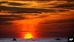 FILE - Lobster fishermen work at sunrise in the Atlantic Ocean, Sept. 8, 2022, off of Kennebunkport, Maine. (AP Photo/Robert F. Bukaty, File)