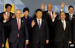 FILE - Leaders wave as they pose for a group family photo at the Asia-Pacific Economic Cooperation (APEC) summit in Manila, Philippines.