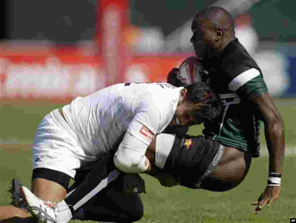 England's Chris Cracknell, left, tackles Fourtune Chipendu from Zimbabwe during the first day of the Dubai Rugby Sevens, Friday, Dec. 2, 2011 in Dubai, United Arab Emirates. (AP Photo/Kamran Jebreili)