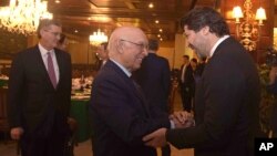 Afghanistan’s deputy foreign minister, Hekmat Khalil Karzai, right, and Pakistani foreign affairs adviser Sartaj Aziz exchange greetings before a four-nation meeting in Islamabad, Jan. 11, 2016. Richard Olson, a U.S. special representative, appears at left.