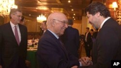 FILE - Afghanistan’s deputy foreign minister, Hekmat Khalil Karzai, right, and Pakistani foreign affairs adviser Sartaj Aziz exchange greetings before a four-nation meeting to develop a peace process for Afghanistan. Richard Olson, U.S. Special Representative for Afghanistan and Pakistan is seen at left. 