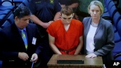 A video monitor shows school shooting suspect Nikolas Cruz, center, making an appearance before Judge Kim Theresa Mollica in Broward County Court in Fort Lauderdale, Florida, Feb. 15, 2018. 