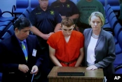 A video monitor shows school shooting suspect Nikolas Cruz (C) making an appearance before Judge Kim Theresa Mollica in Broward County Court, Thursday, Feb. 15, 2018, in Fort Lauderdale, Fla.