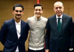 FILE - Turkey's President Recep Tayyip Erdogan, right, poses for a photo with soccer players Ilkay Gundogan, left and Mesut Ozil, center, in London, Britain, May 13, 2018.
