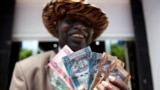 FILE - A man from South Sudan displays currency outside the Central Bank of South Sudan in Juba. The commissioner-general of South Sudan’s National Revenue Authority says the country is collecting far less revenue than it should.