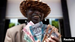 FILE - A man from South Sudan displays currency outside the Central Bank of South Sudan in Juba. The commissioner-general of South Sudan’s National Revenue Authority says the country is collecting far less revenue than it should.