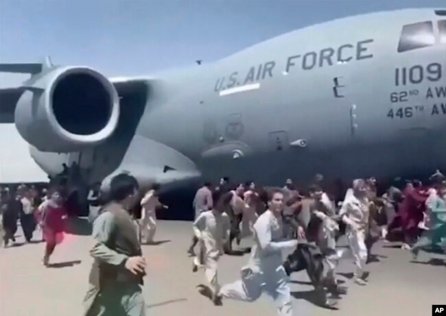Ratusan orang berlari di samping pesawat Angkatan Udara AS di landasan bandara internasional, di Kabul, Afghanistan, Senin, 16 Agustus 2021. (Foto: AP)