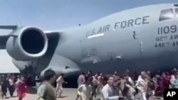 Ratusan orang berlarian di samping pesawat angkut C-17 Angkatan Udara AS saat bergerak di landasan bandara internasional, di Kabul, Afghanistan, Senin, 16 Agustus 2021. (Verified UGC via AP)
