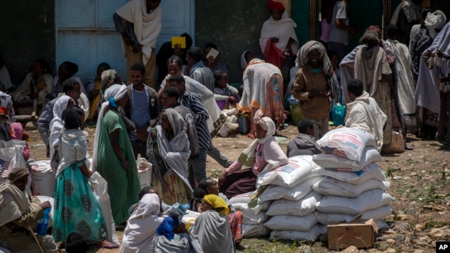 FILE - An Ethiopian woman sits on sacks of wheat to be distributed by the Relief Society of Tigray in the town of Agula, in the Tigray region of northern Ethiopia, May 8, 2021.